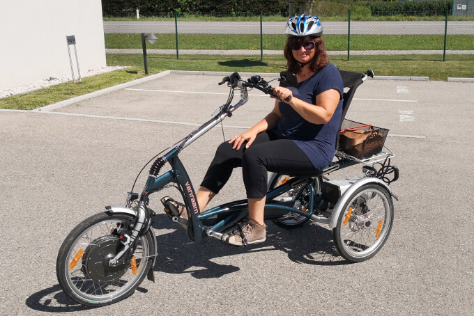 Foto: Andrea fährt auf dem Parkplatz auf ihrem neuen Therapiefahrrad